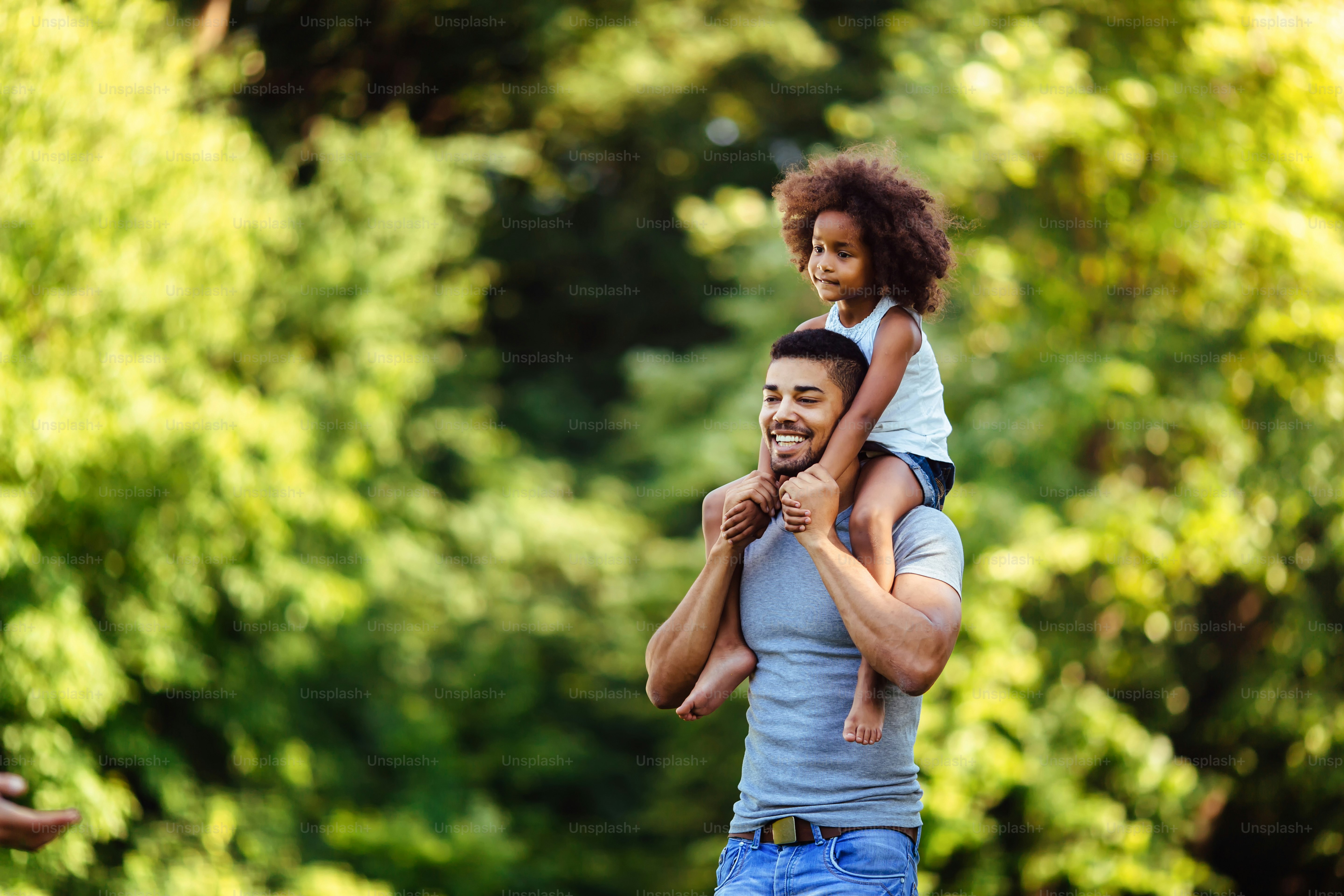 Portrait of young father carrying his daughter on his back in nature