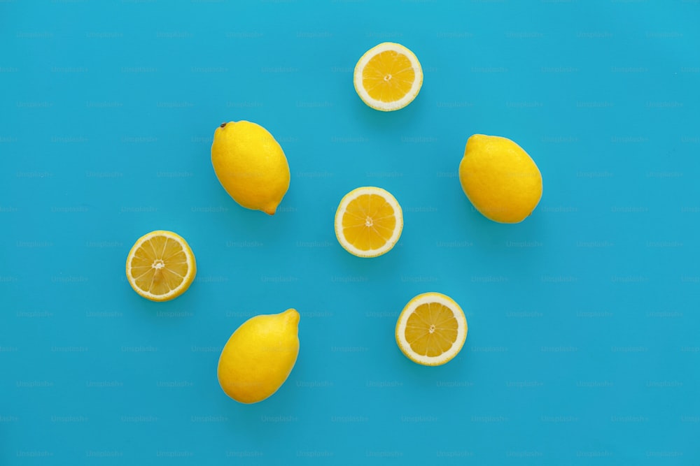 yellow lemons  and slices of lemon on bright blue paper, trendy flat lay. fruits modern image, top view. juicy summer vitamin and diet concept. pop art style. creative minimalism pattern