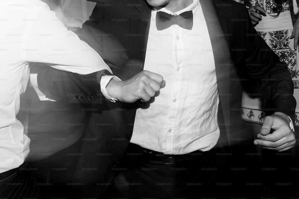 stylish men having fun and dancing at party in restaurant, reception at luxury wedding, rich graduation, black and white photo