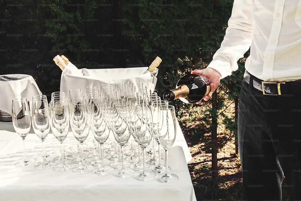 waiter pours stylish luxury glasses for champagne on a table for a celebration, cathering in the restaurant