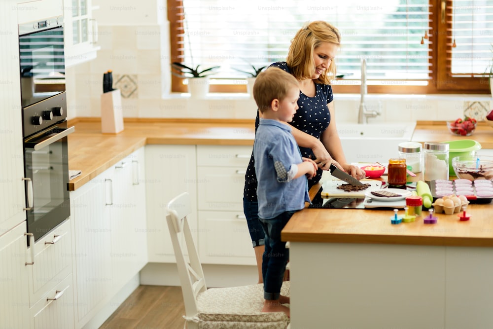 Smart cute child helping mother in kitchen preparing cookies