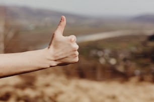 mão da mulher mostrando como com o polegar para cima no fundo das montanhas ensolaradas, aprovação e conceito de viagem