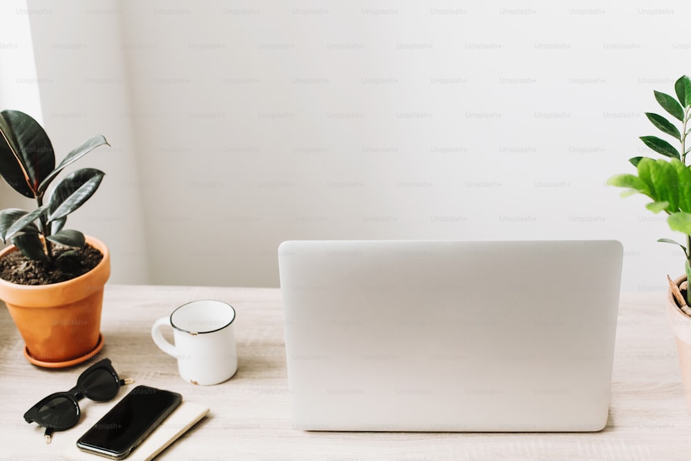 Freelance concept. Desktop with laptop, phone, notebook, coffee cup and plant. business workspace in home or office with work tools on wooden table. stylish work place