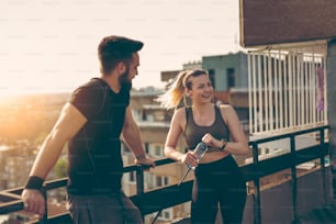Young couple standing on a building rooftop terrace, getting ready for workout