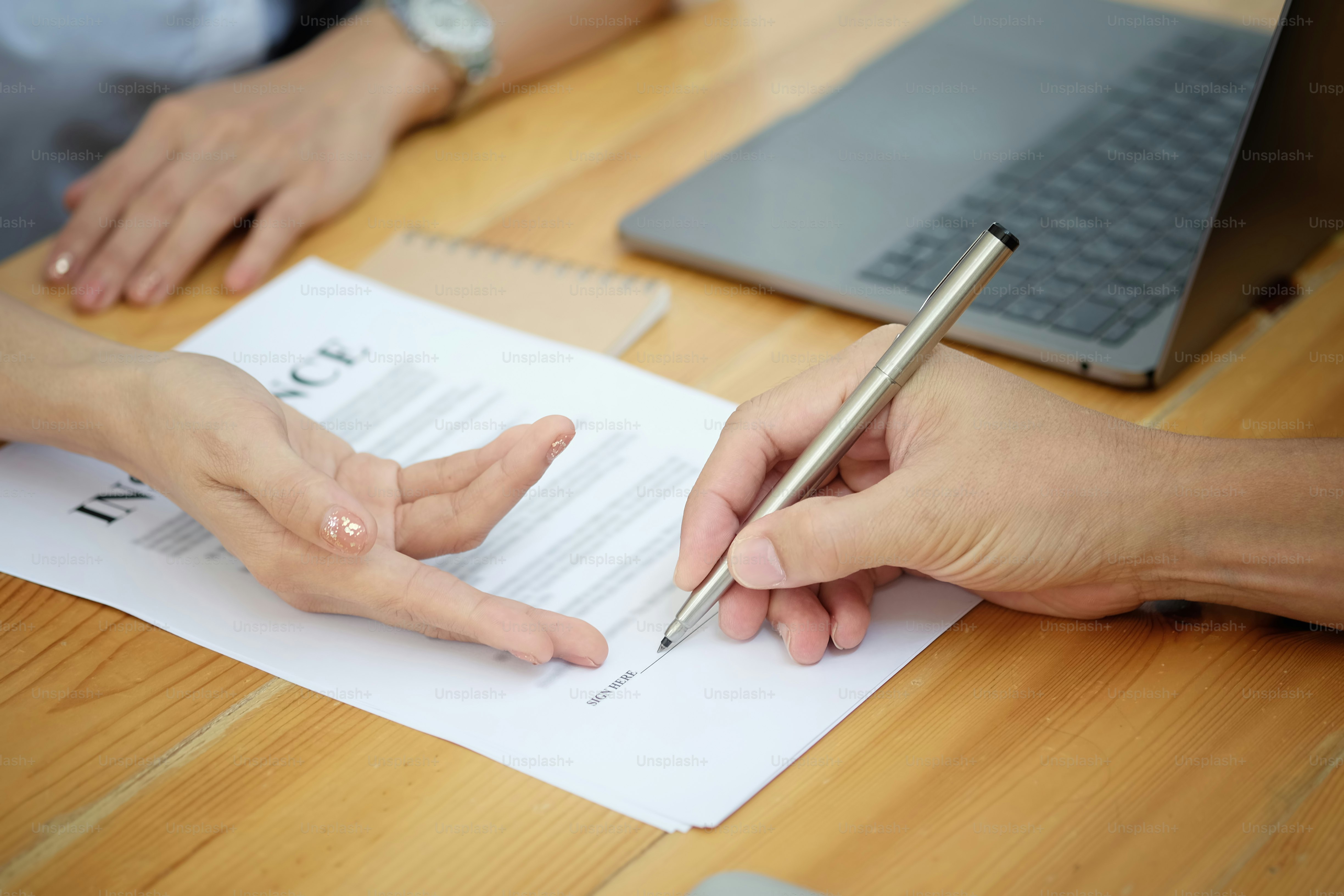 Man signing a car insurance policy, the agent is pointing the document