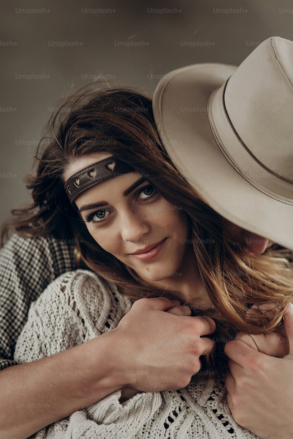 Bello uomo cowboy alla moda in cappello e camicia che abbraccia bella donna gypsu da dietro, coppia sensuale sorridente, primo piano