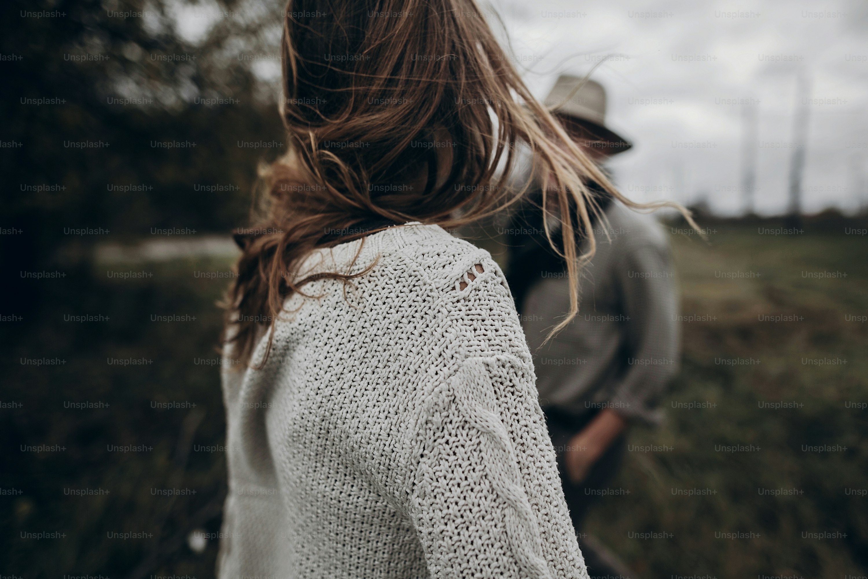 boho gypsy woman and man in hat embracing in windy field.stylish hipster couple dancing. atmospheric motion moment. fashionable look. rustic wedding concept