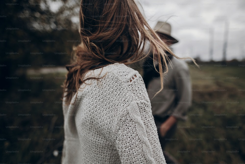 boho gypsy woman and man in hat embracing in windy field.stylish hipster couple dancing. atmospheric motion moment. fashionable look. rustic wedding concept