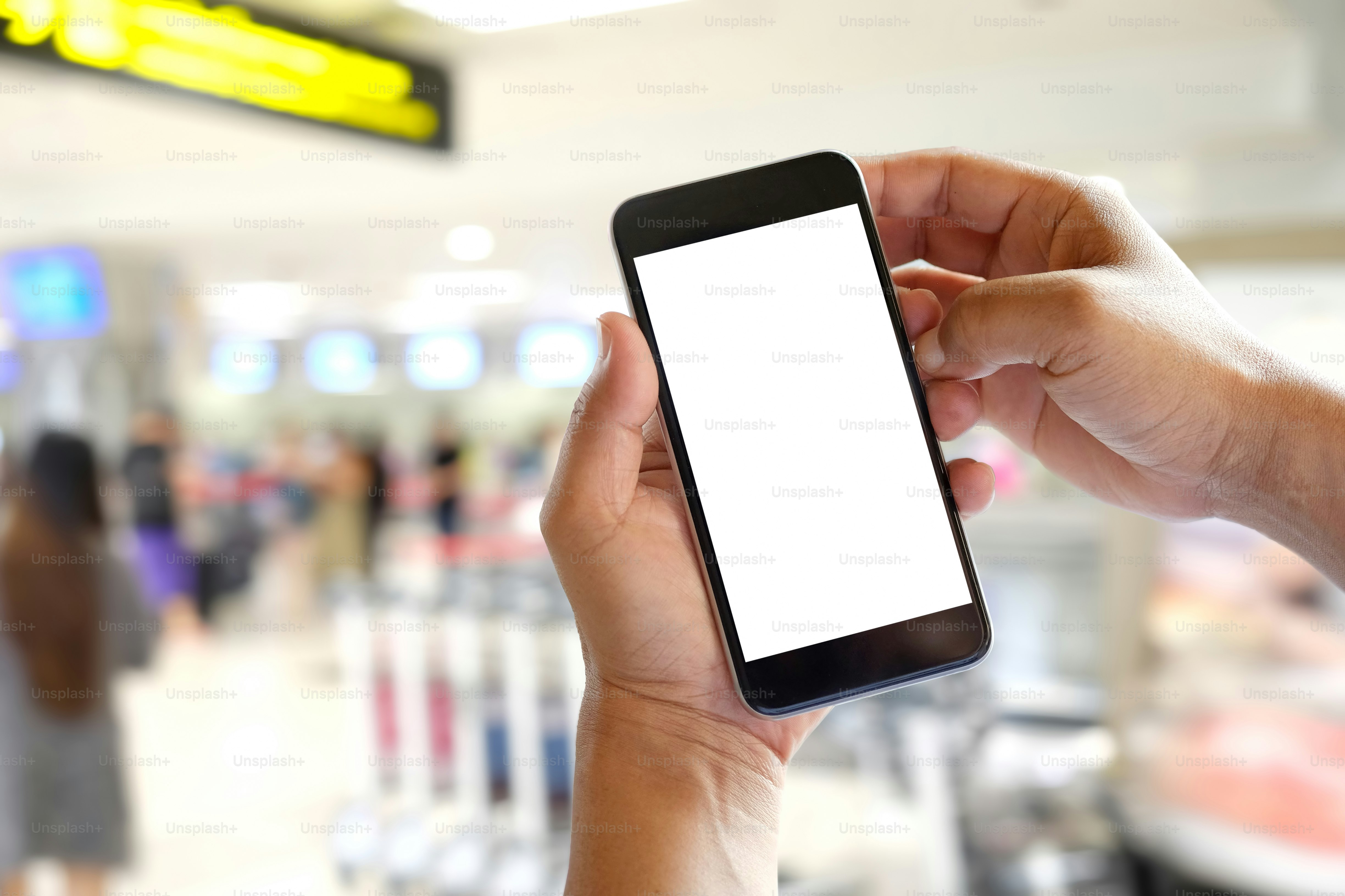 Businessman using smartphone at airport."nBlank screen mobile phone for graphic display montage.