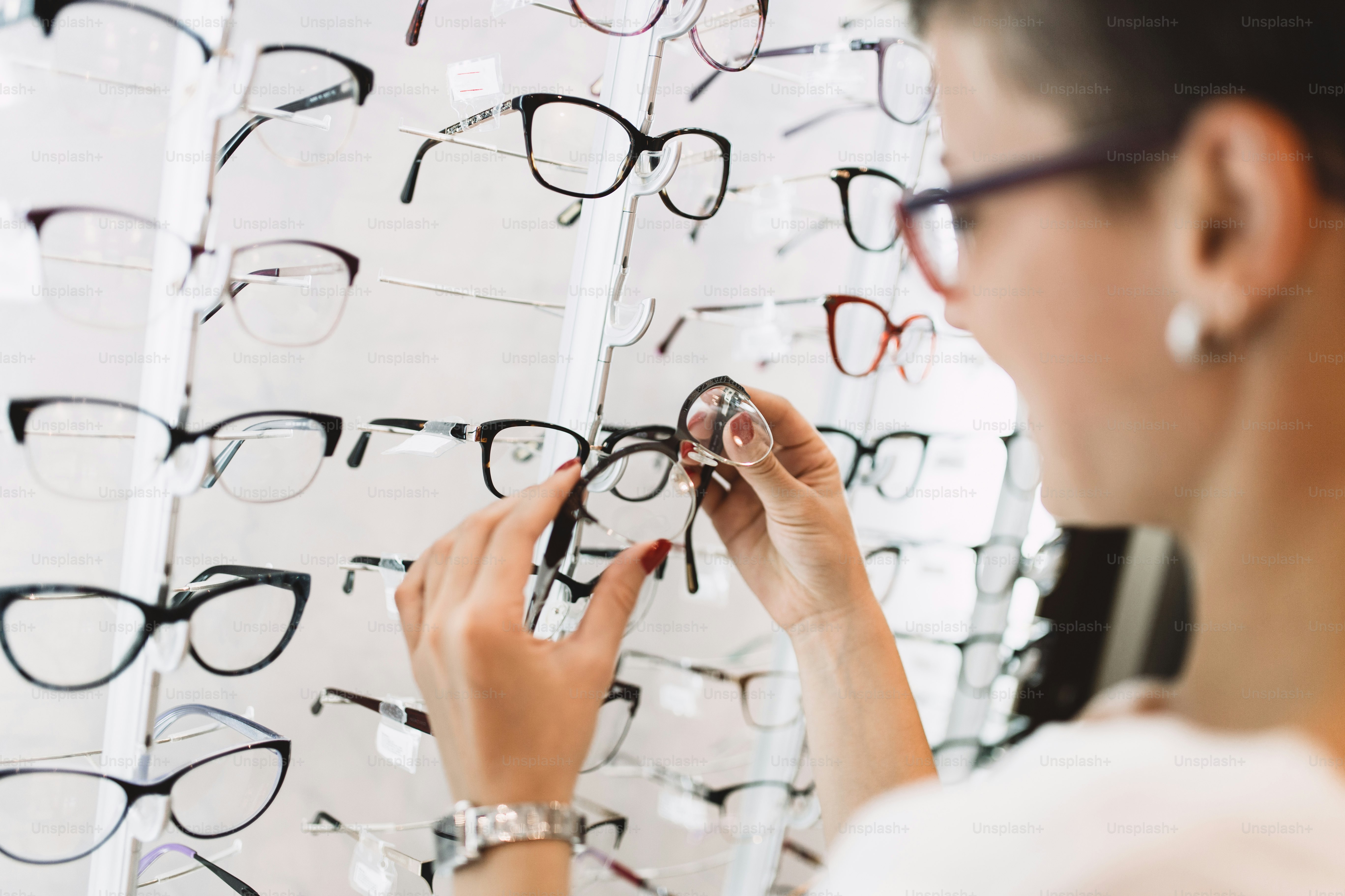 Belle femme d’âge moyen choisissant des lunettes dans un magasin d’optique.