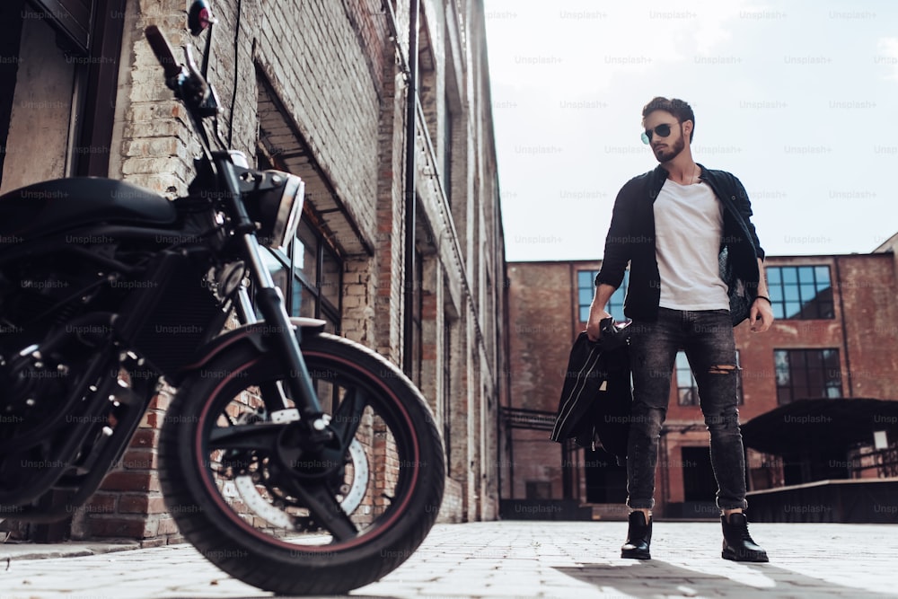 Handsome bearded biker with classic style black motorcycle. Cafe racer.