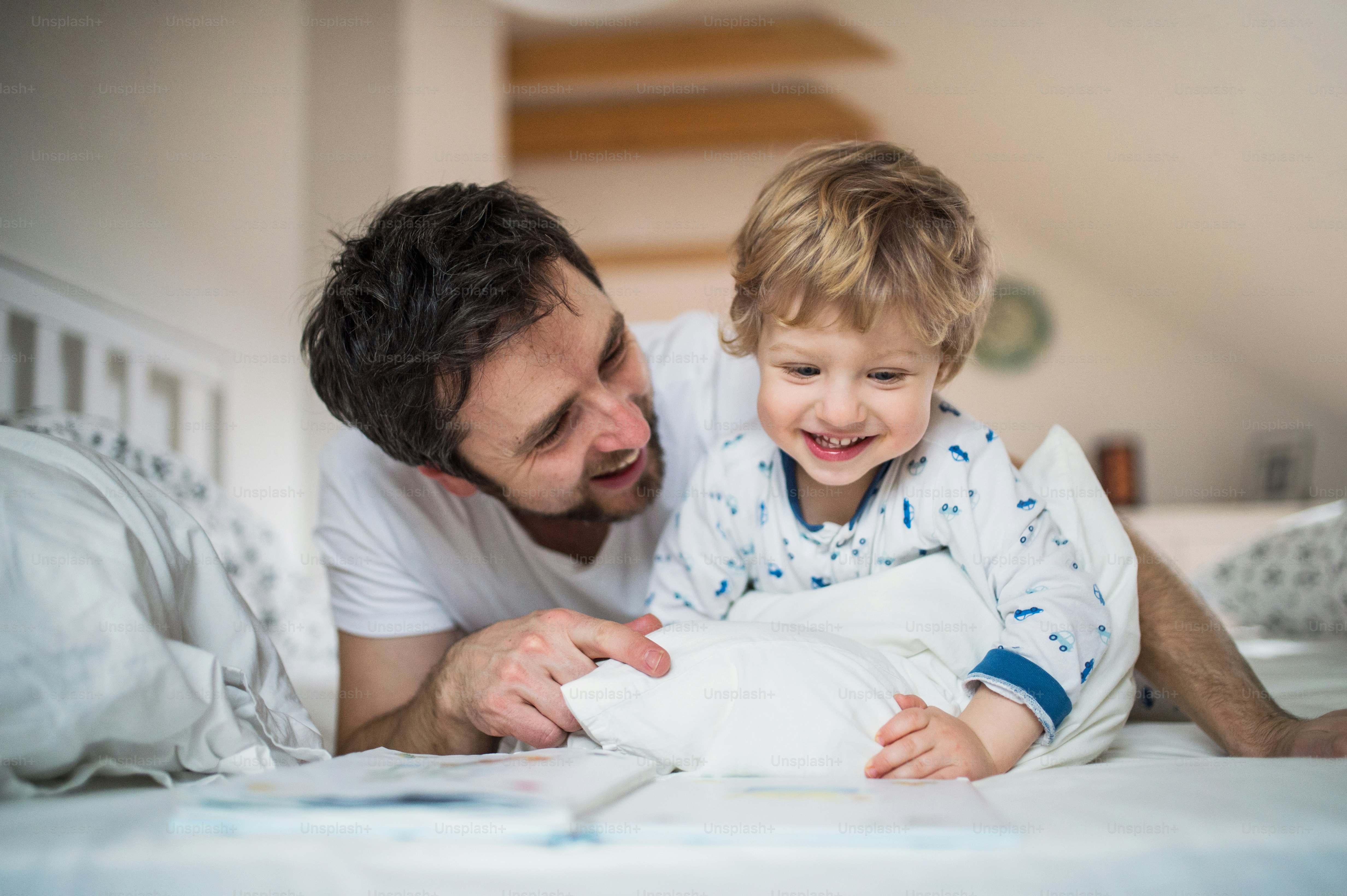 自宅の寝室で幼児の男の子を持つ成熟した父親、就寝時に物語を読んでいます。育児休暇。