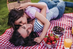 Beautiful young mother with daughter on a picnic. Hugs and kisses to lovely mom