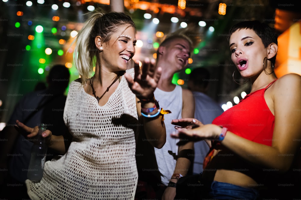Jóvenes amigos felices divirtiéndose en un festival de música