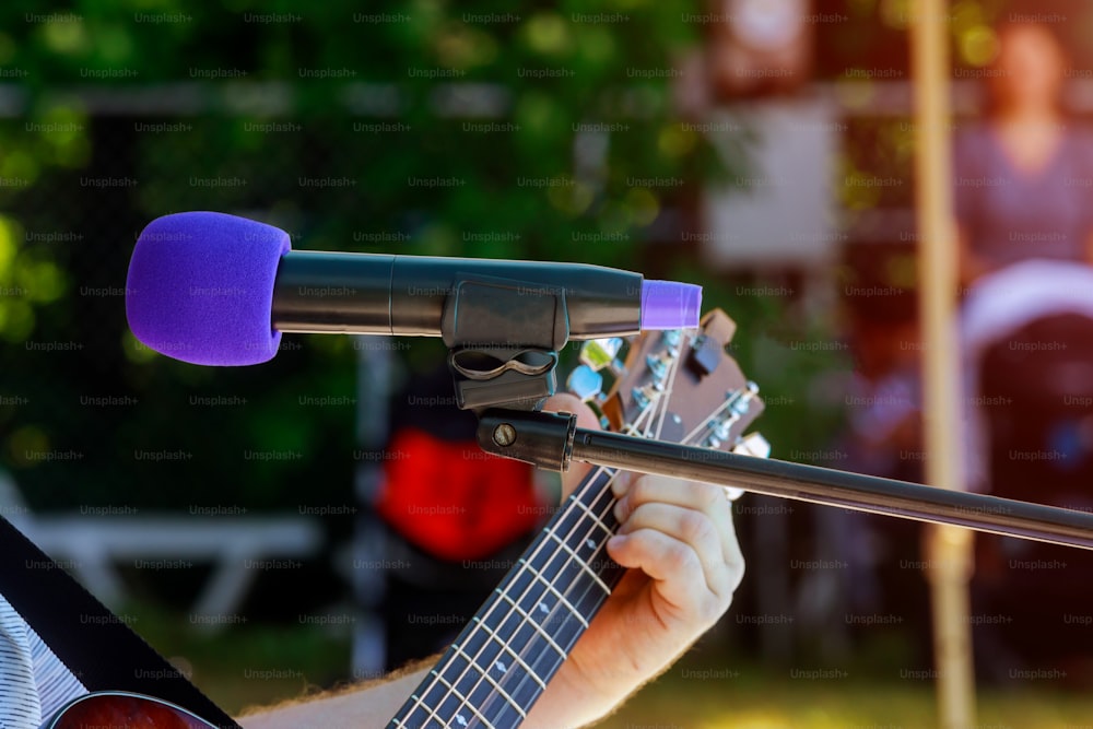 male musician playing acoustic guitar behind condenser microphone in recording microphone musician