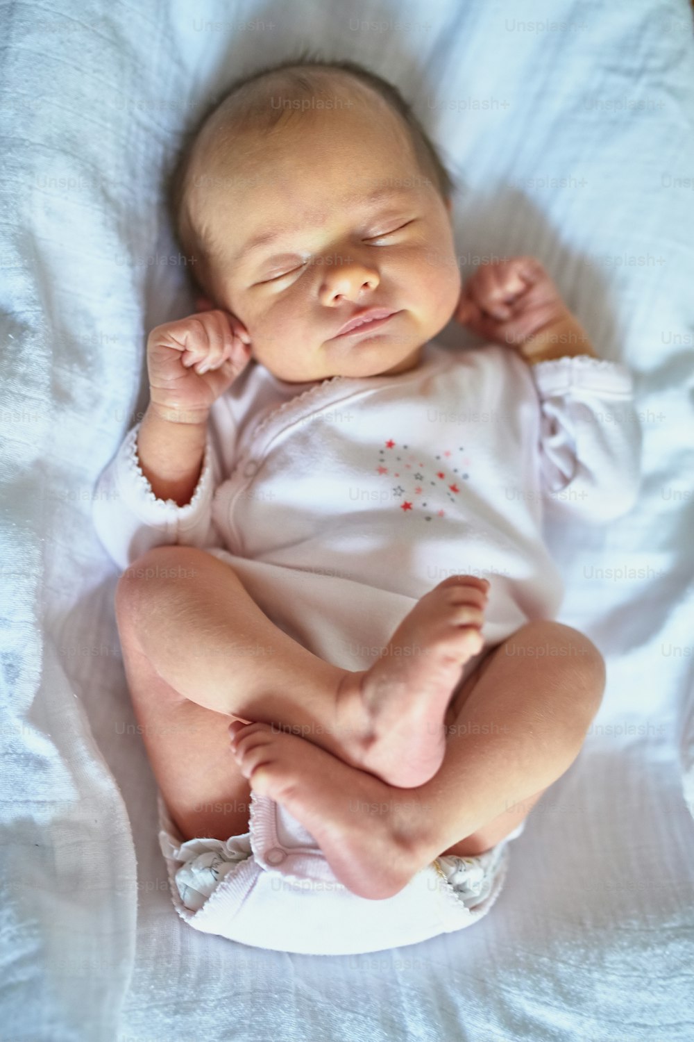 Adorable newborn baby girl sleeping in bed at home