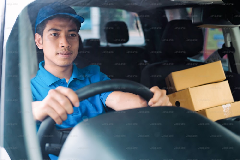 Delivery driver driving car with packages on seat outside the warehouse