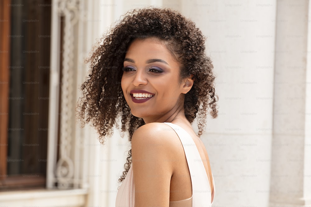 Beauty portrait of african american woman with gorgeous toothy smile, glamour makeup and long curly hair.