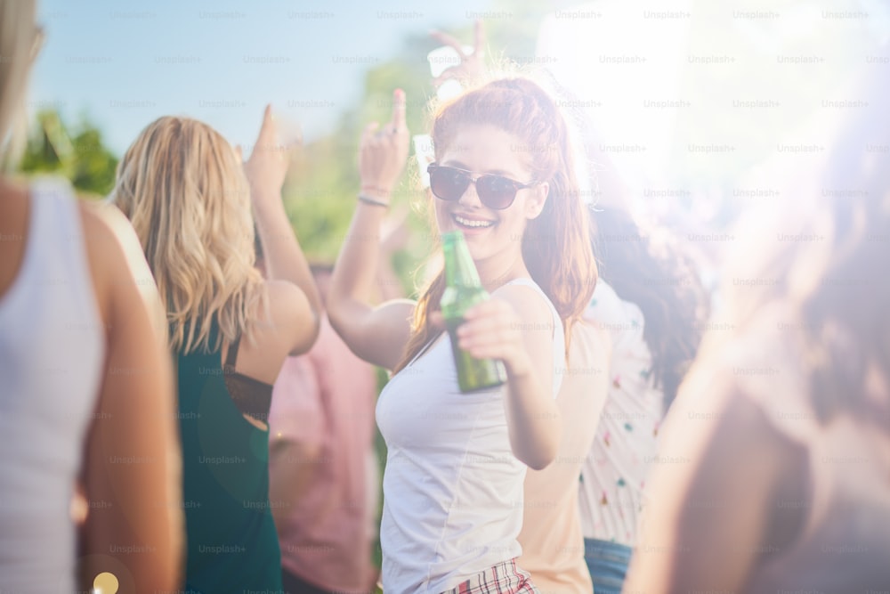 Ginger girl dancing, drinking an having a good time at outdoor party