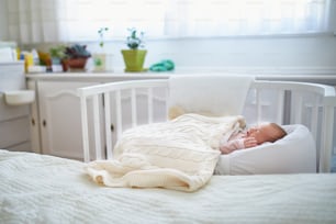 Bébé nouveau-né faisant une sieste dans un berceau cododo attaché au lit des parents