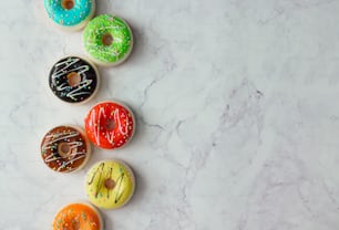 Creative arrangement of colorful donuts on marble background. Minimal food concept. Flat lay.
