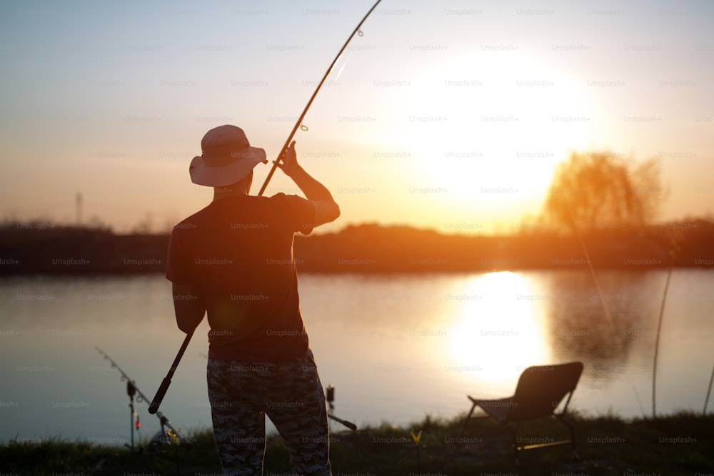 Pesca como recreação e esportes exibidos pelo pescador no lago durante o pôr do sol