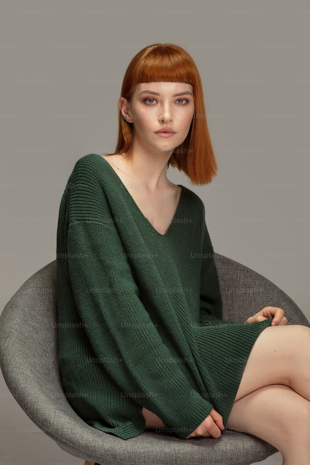 Beautiful natural redhead woman posing in fashionable sweater, looking at camera.