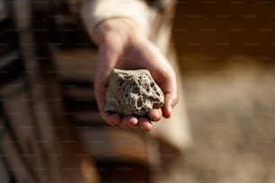 boho woman holding in hand moon shaped textured stone at river beach