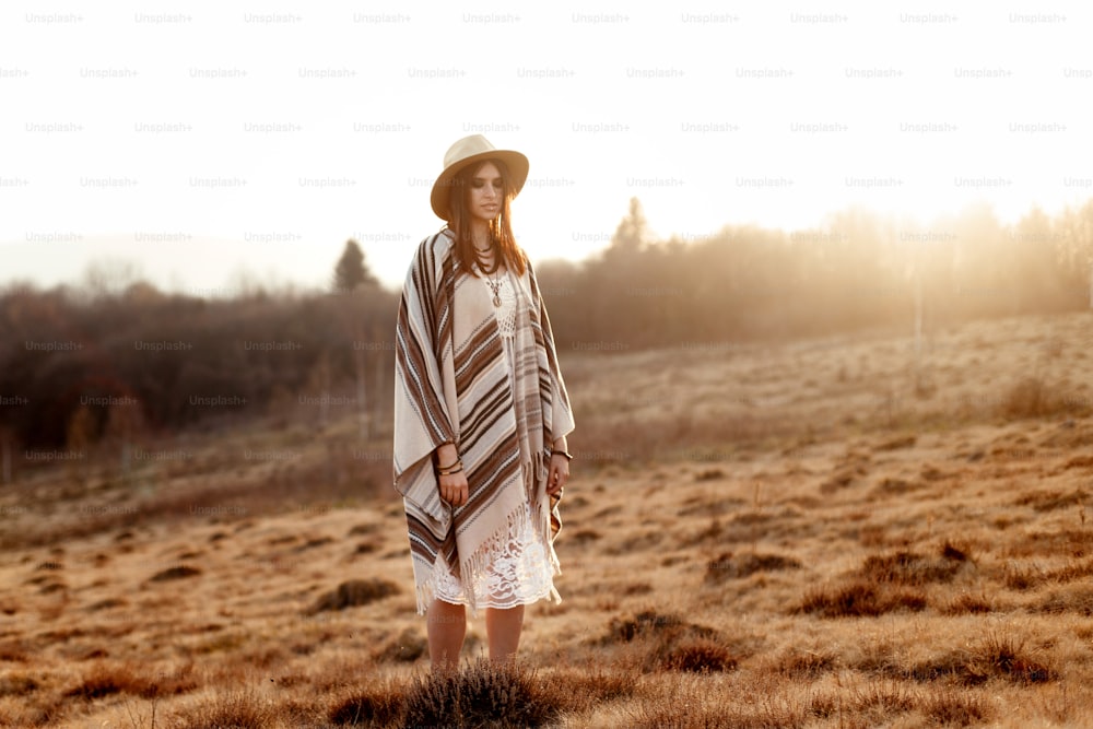 beautiful boho woman hipster enjoying sunset and posing at sun light  in mountains, space for text, amazing moment