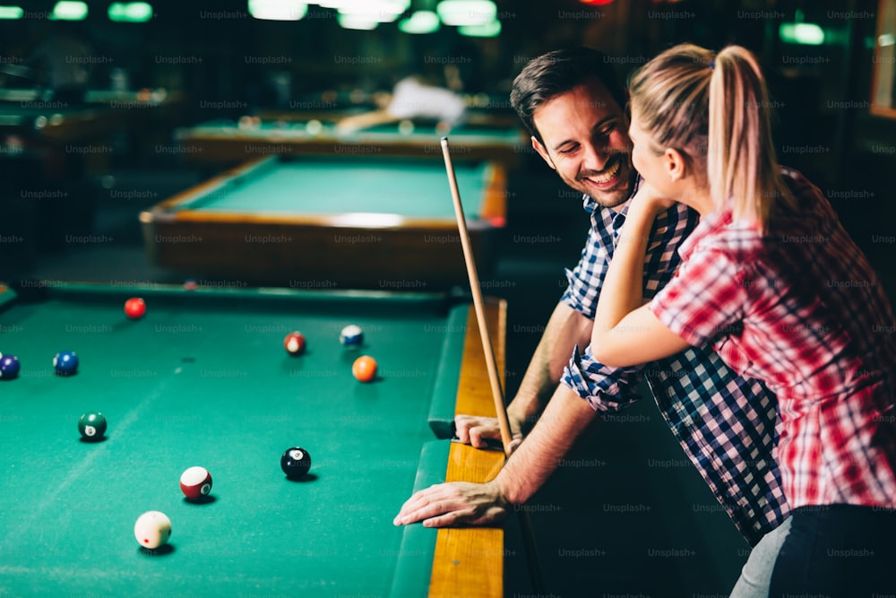 Young attractive couple playing snooker together in bar