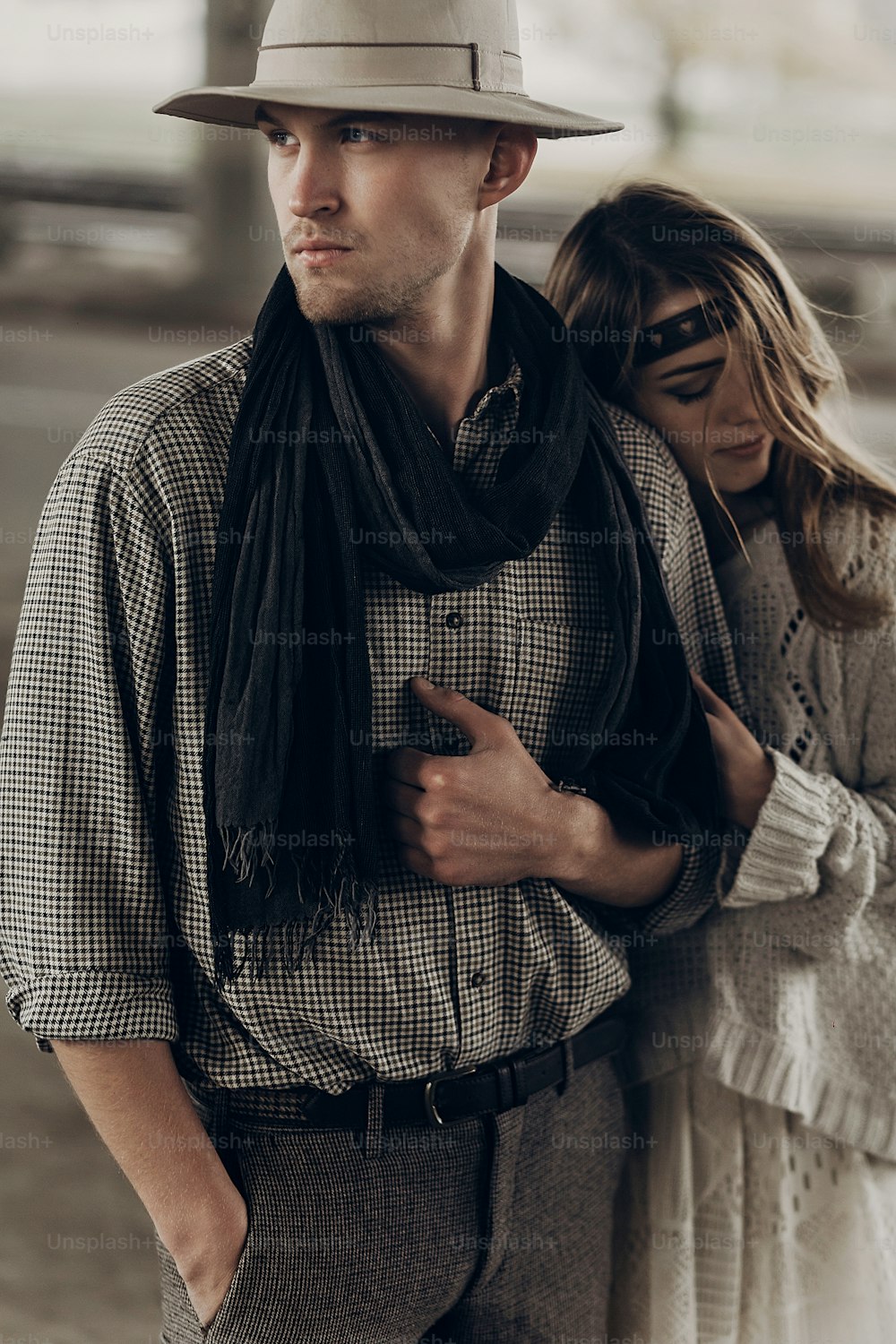 Femme gitane romantique dans des vêtements bohèmes élégants et une robe blanche étreignant un bel homme cow-boy en chapeau blanc et écharpe