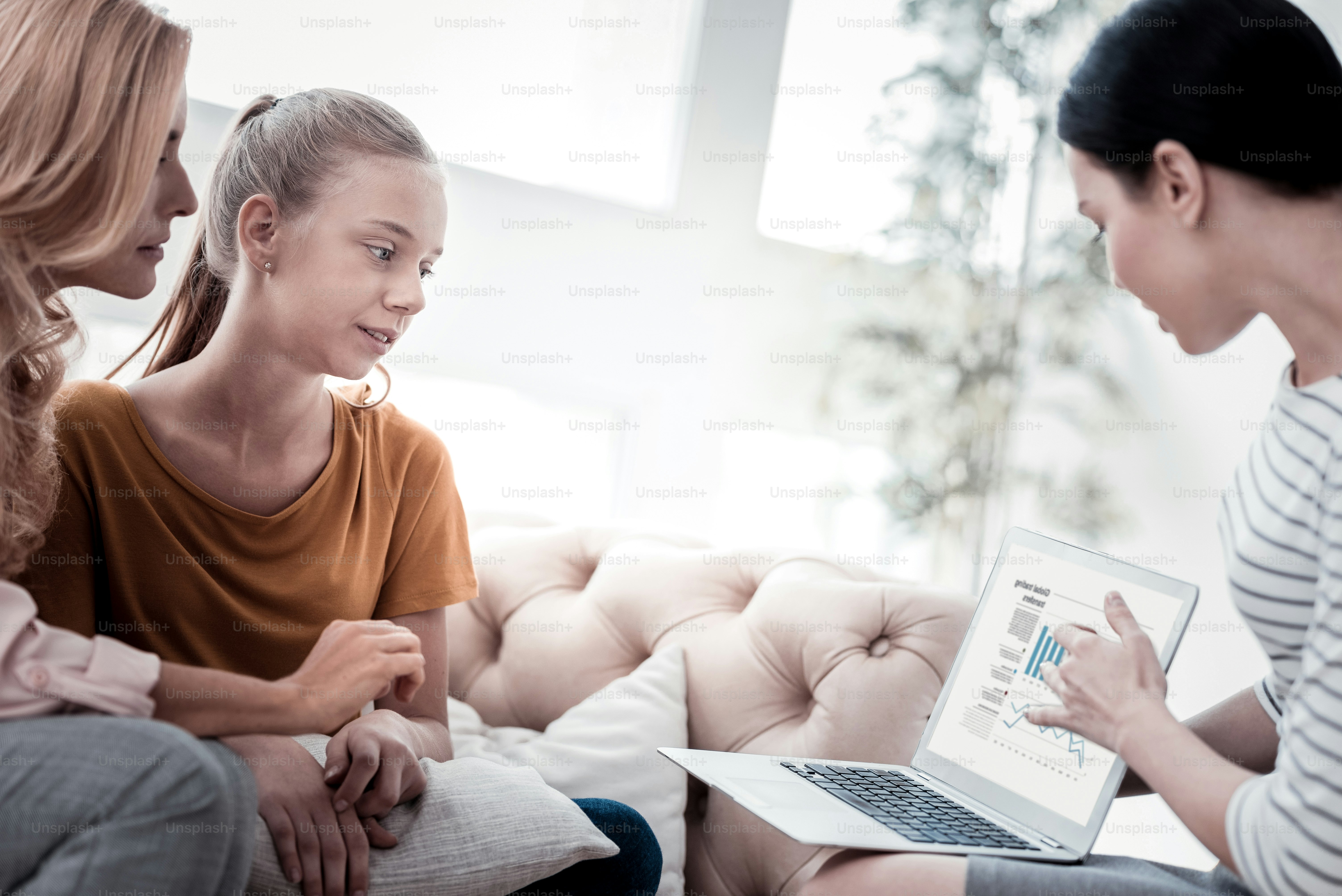 Useful information. Attentive family listening to psychologist using a laptop and presenting girls tests statics