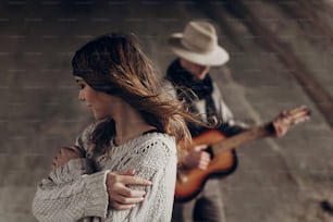 Menina indie sensual bonita em roupas boho hipster posando na frente do guitarrista cowboy bonito ao ar livre