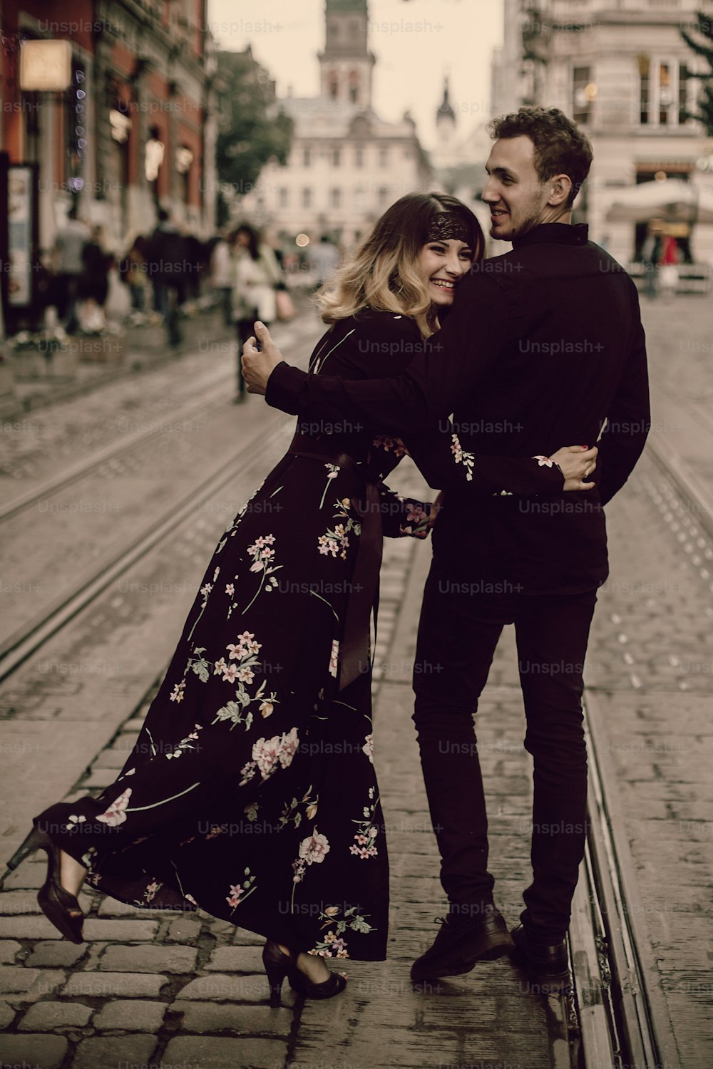 stylish gypsy couple in love walking and smiling in evening city street. woman and man gently embracing, funny romantic french atmospheric moment. love mood. back view