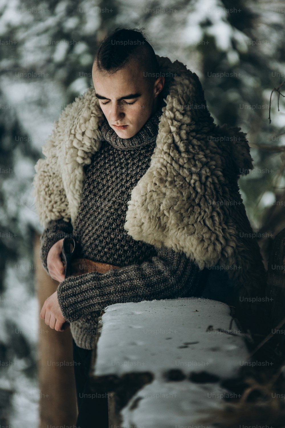 guerrero vikingo con hacha de acero posando cerca de una cabaña de madera en el bosque invernal escandinavo, cosplay vikingo de thor, traje tradicional noruego, hombre guapo con peinado mohawk parado al aire libre