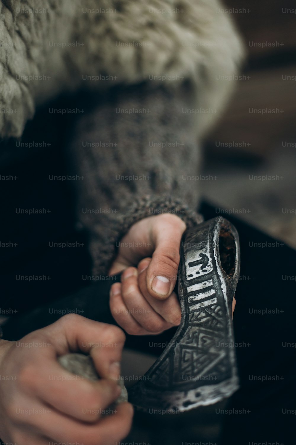 Northern warrior with weapon, viking sharpening his axe before battle hands close-up, scandinavian lumberjack with steel axe, viking costume cosplay, norway historical heritage concept
