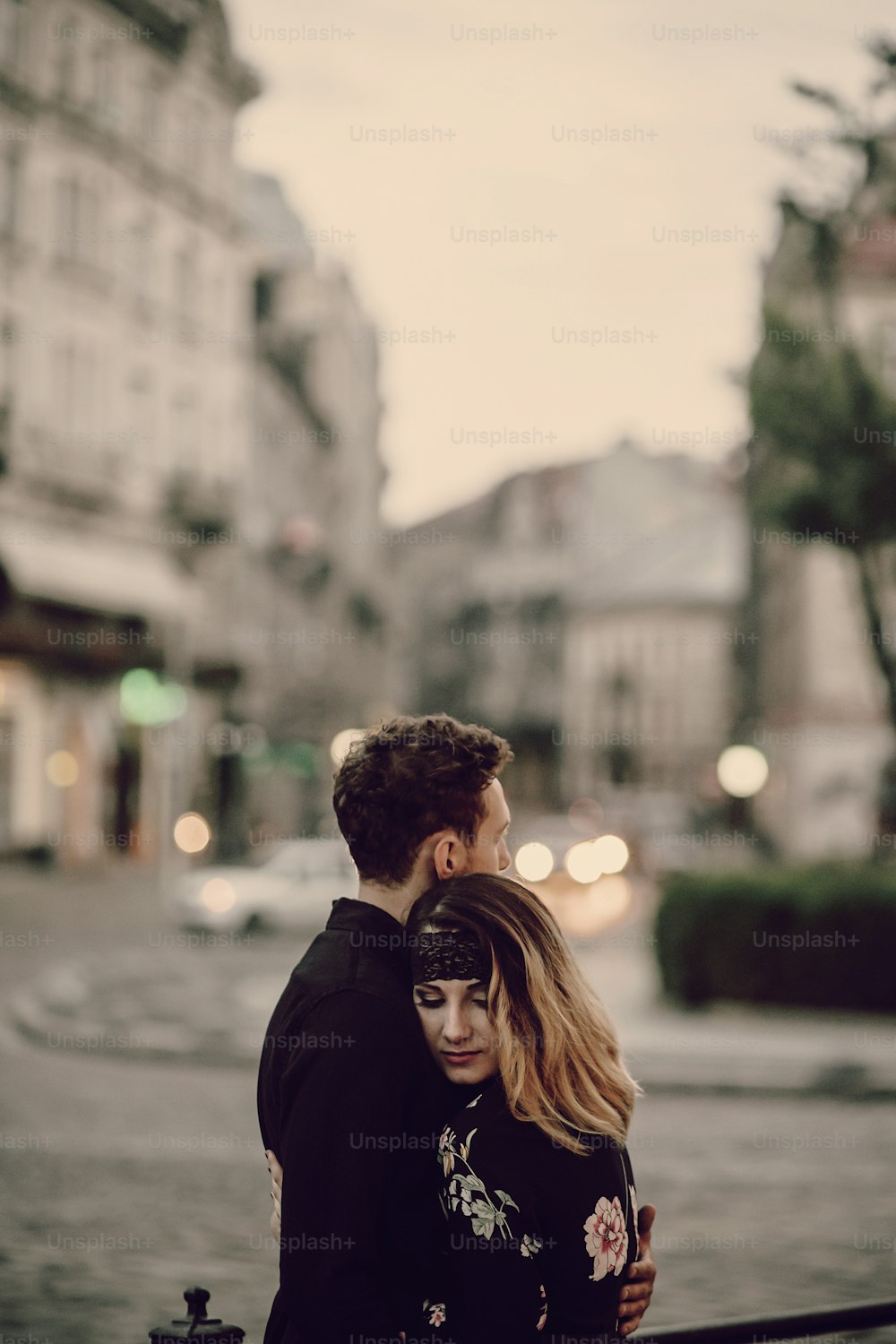 elegante casal cigano apaixonado abraçando-se na rua da cidade à noite em luzes de carro em movimento. mulher e homem abraçando, romântico momento atmosférico francês. humor de amor apaixonado.