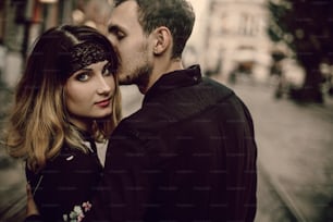 stylish gypsy couple in love kissing hugging in evening city street. woman and man gently embracing, romantic french atmospheric moment. love mood. gypsy wedding