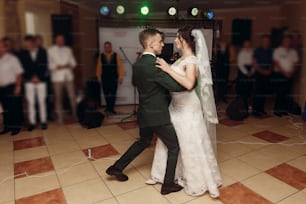 gorgeous bride and stylish groom dancing at wedding party in restaurant reception. happy luxury wedding couple having first dance