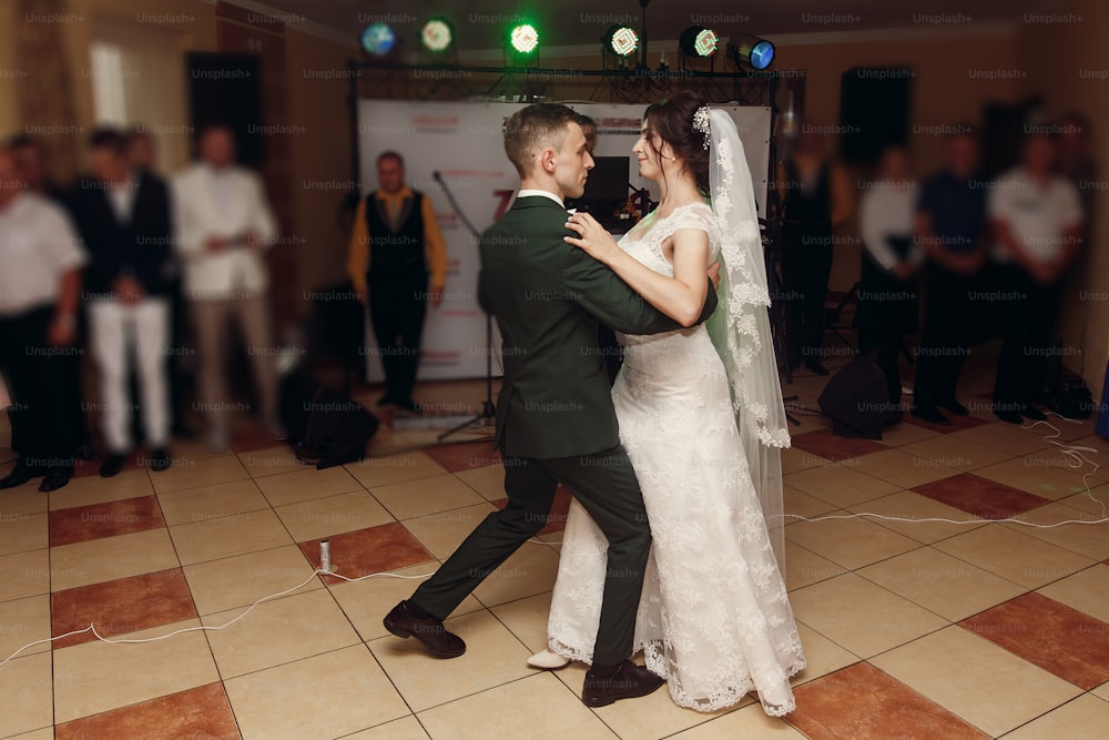 gorgeous bride and stylish groom dancing at wedding party in restaurant reception. happy luxury wedding couple having first dance