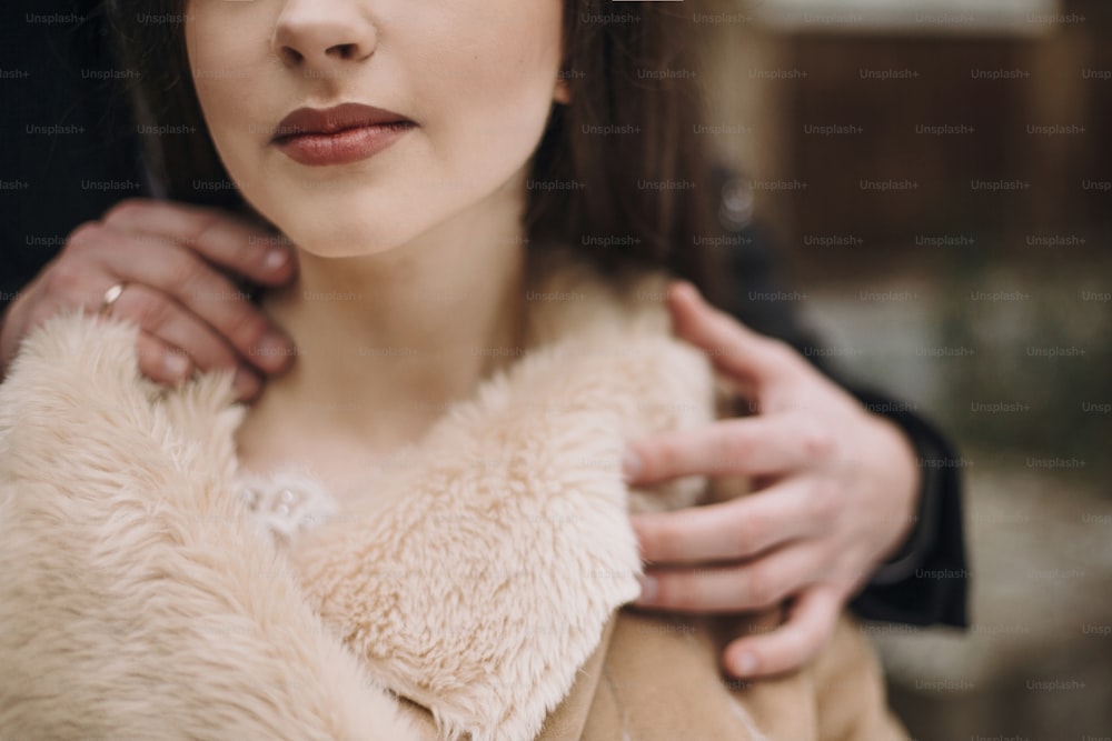 stylish groom sensually hugging gorgeous bride neck at wooden house. wedding couple embracing in snowy park. barn wedding. romantic sensual moment of newlyweds