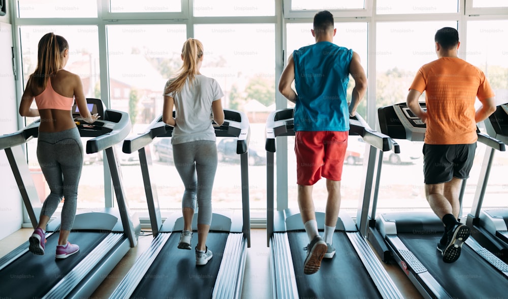 Healthy man and woman running on a treadmill in a gym. Sport and health concept