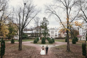 splendida sposa con bouquet e sposo elegante che cammina al vecchio castello nel parco europeo in autunno. felice coppia di sposi che si abbracciano. momento romantico e sensuale degli sposi