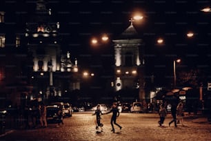 lovers running through empty road in the evening city street. stylish couple in love having fun and holding hands in city lights. modern woman and man romantic french atmospheric moment