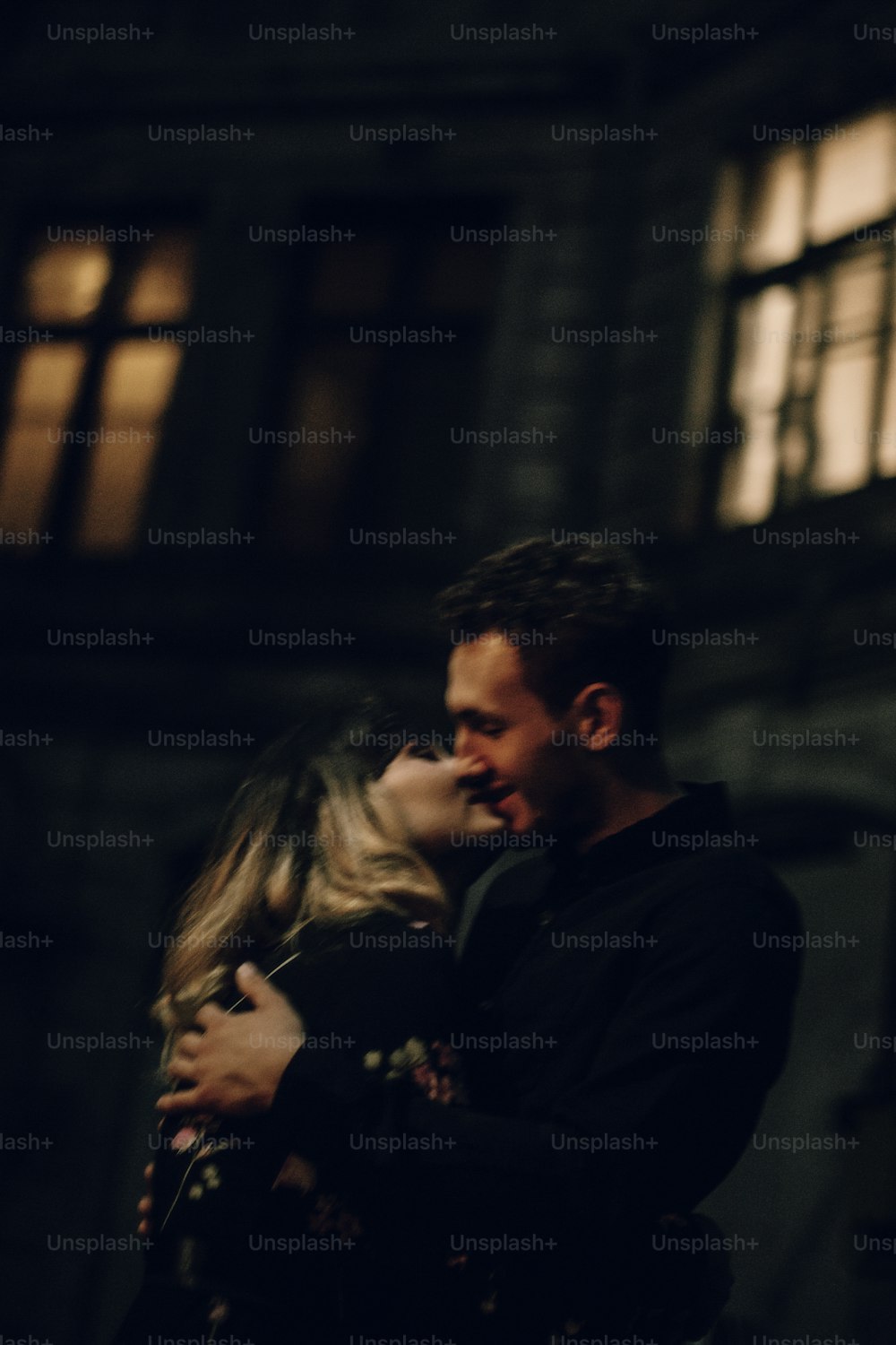 Stilvolles Zigeunerpaar verliebt umarmt sich in der abendlichen Stadtstraße im alten Gebäude. Frau und Mann küssen sich sanft, romantischer französischer atmosphärischer Moment. Liebesstimmung. verschwommenes unscharfes Foto