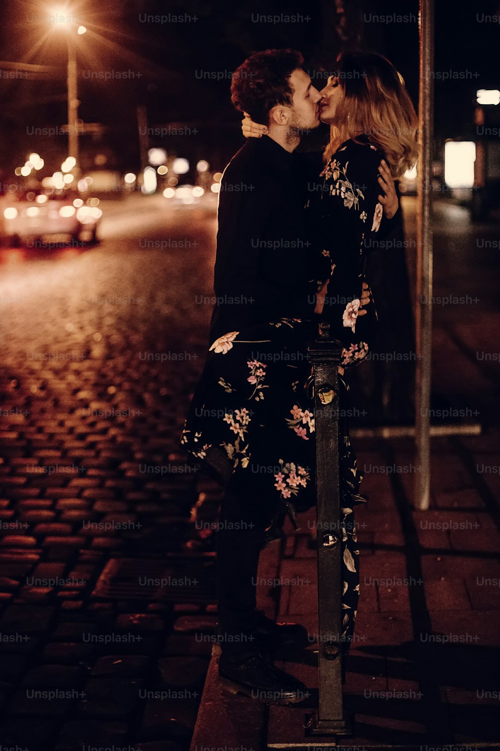 amantes apasionados besándose en la calle de la ciudad de la tarde en la carretera. Elegante pareja gitana enamorada abrazada en las luces nocturnas de la ciudad. Mujer y hombre modernos románticos franceses momento atmosférico