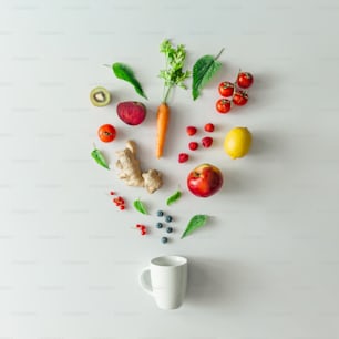 Creative food layout with fruits, vegetables and leaves on bright marble table background with tea cup. Minimal healthy drink concept. Flat lay.