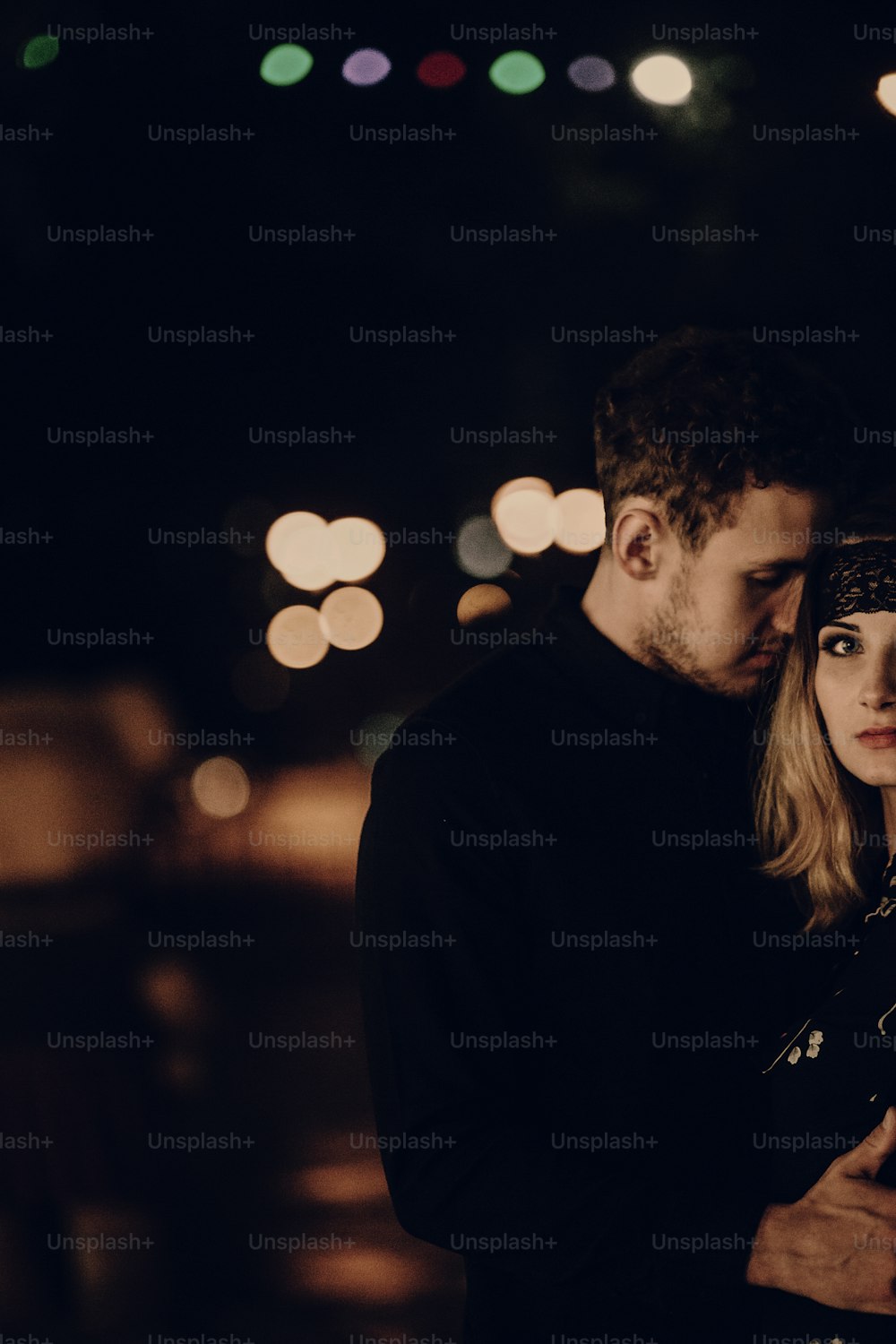 Happy couple hugging in the street at night, handsome man embracing beautiful girlfriend outdoors portrait, romance concept