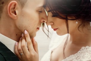 gorgeous bride and stylish groom gently hugging in sunny light. sensual tender emotional moment of luxury wedding couple embracing. portraits