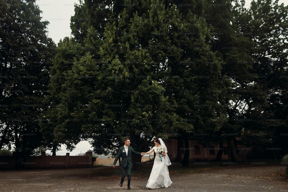 Stilvolle Luxus-Braut und Bräutigam laufen und Spaß bei der Hochzeitsfeier haben. Emotionaler Moment des schönen Hochzeitspaares